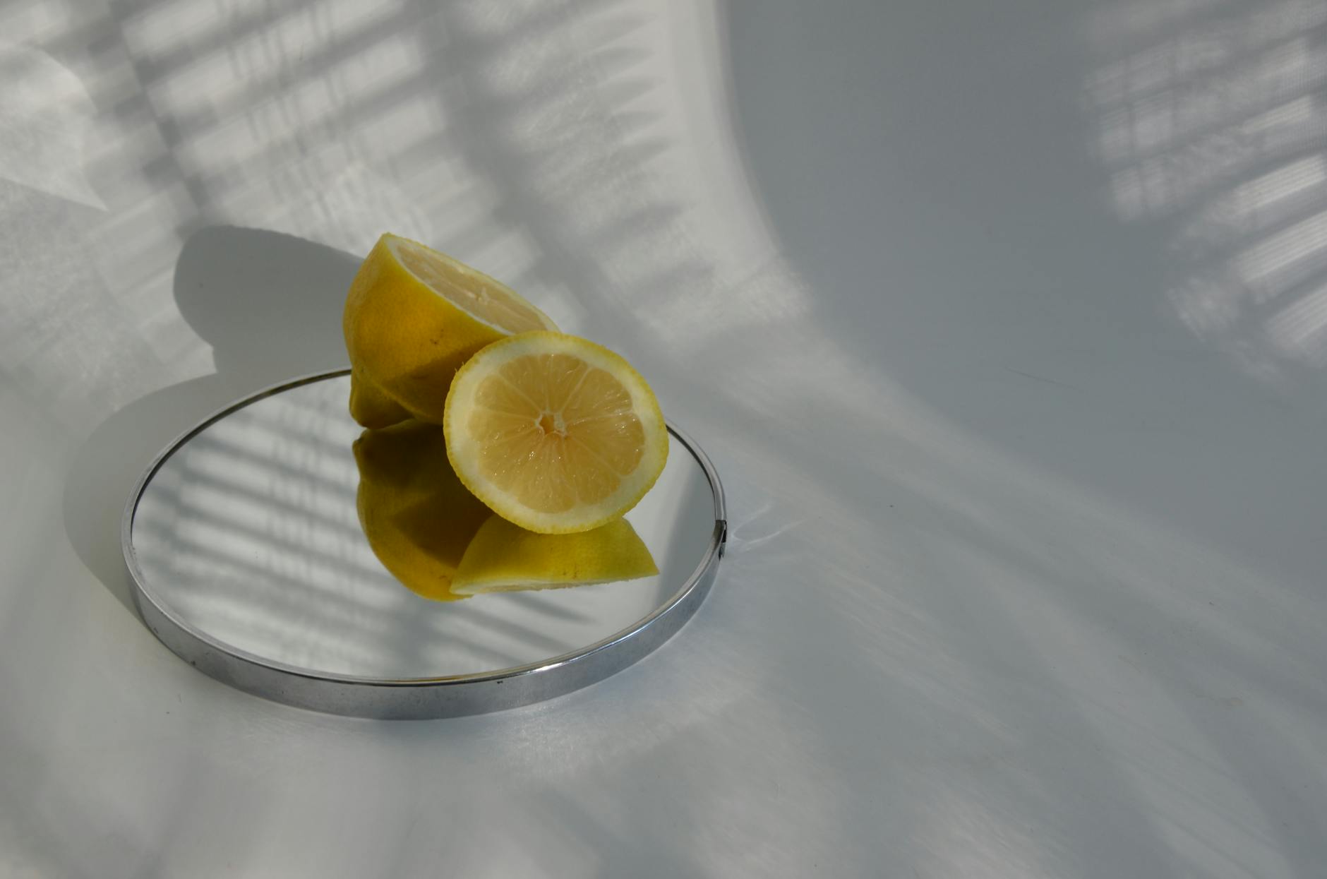 Hand holding a bright yellow lemon on soft pink background with additional lemons, representing the clean and simple approach to intimate wellness.
