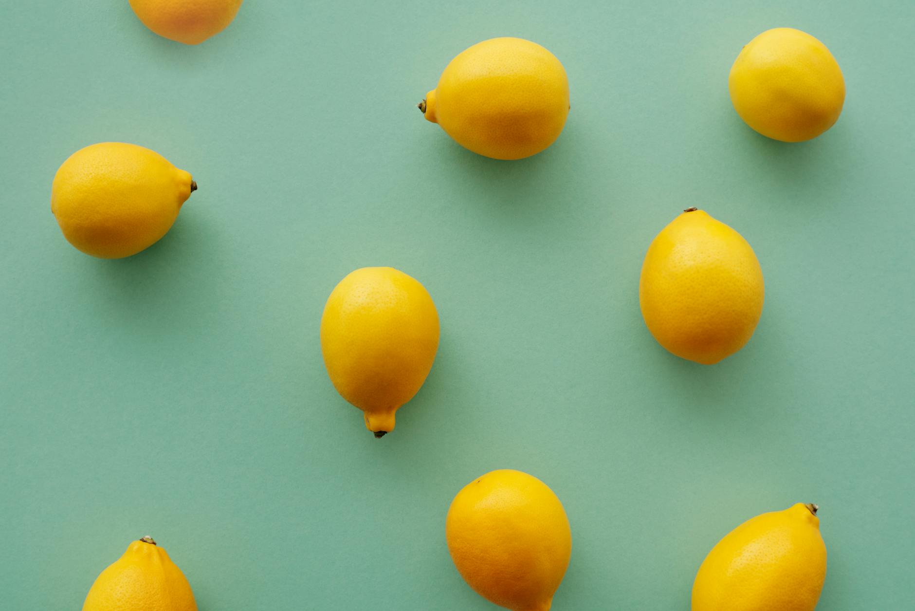 Bright yellow lemons arranged on a pastel green background, representing freshness and vitality
