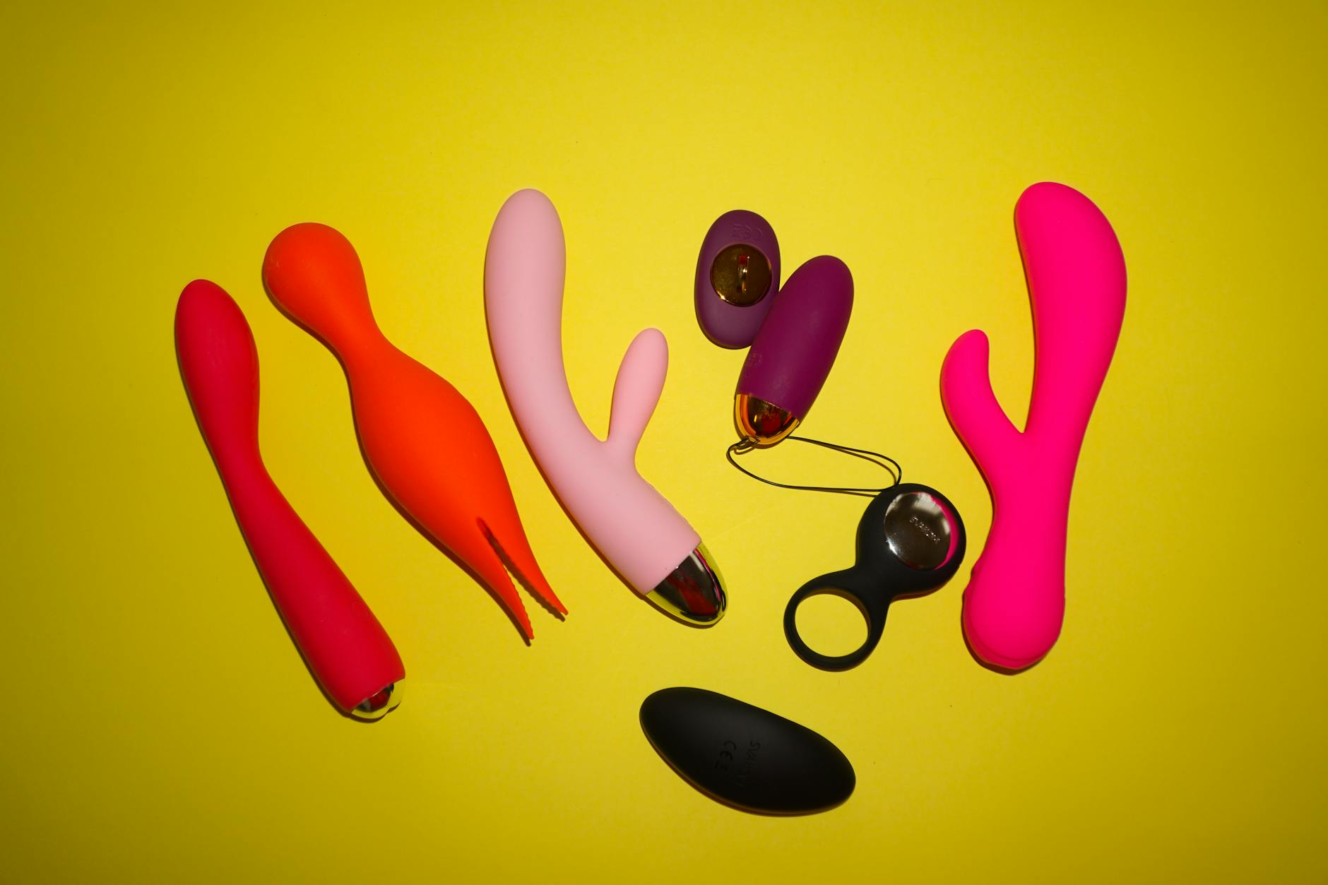Colorful adult toys arranged on a bright yellow background